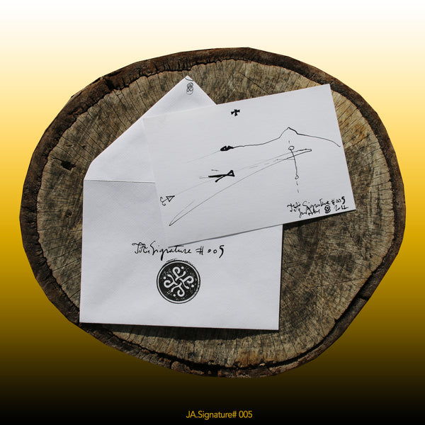 JA.SIGNATURE#005 NFT created from the physical collection JA.Signature by James Arax. On the picture : On a log, in the foreground the JA.Signature paper card and below the envelope with the number of the NFT t and james sign (LogoType).