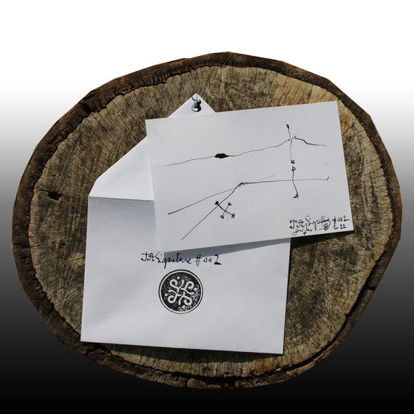 JA.Signature#2 NFT created from the physical collection JA.Signature by James Arax. On the picture : On a log, in the foreground the JA.Signature paper card and below the envelope with the number of the nft and james sign (LogoType).